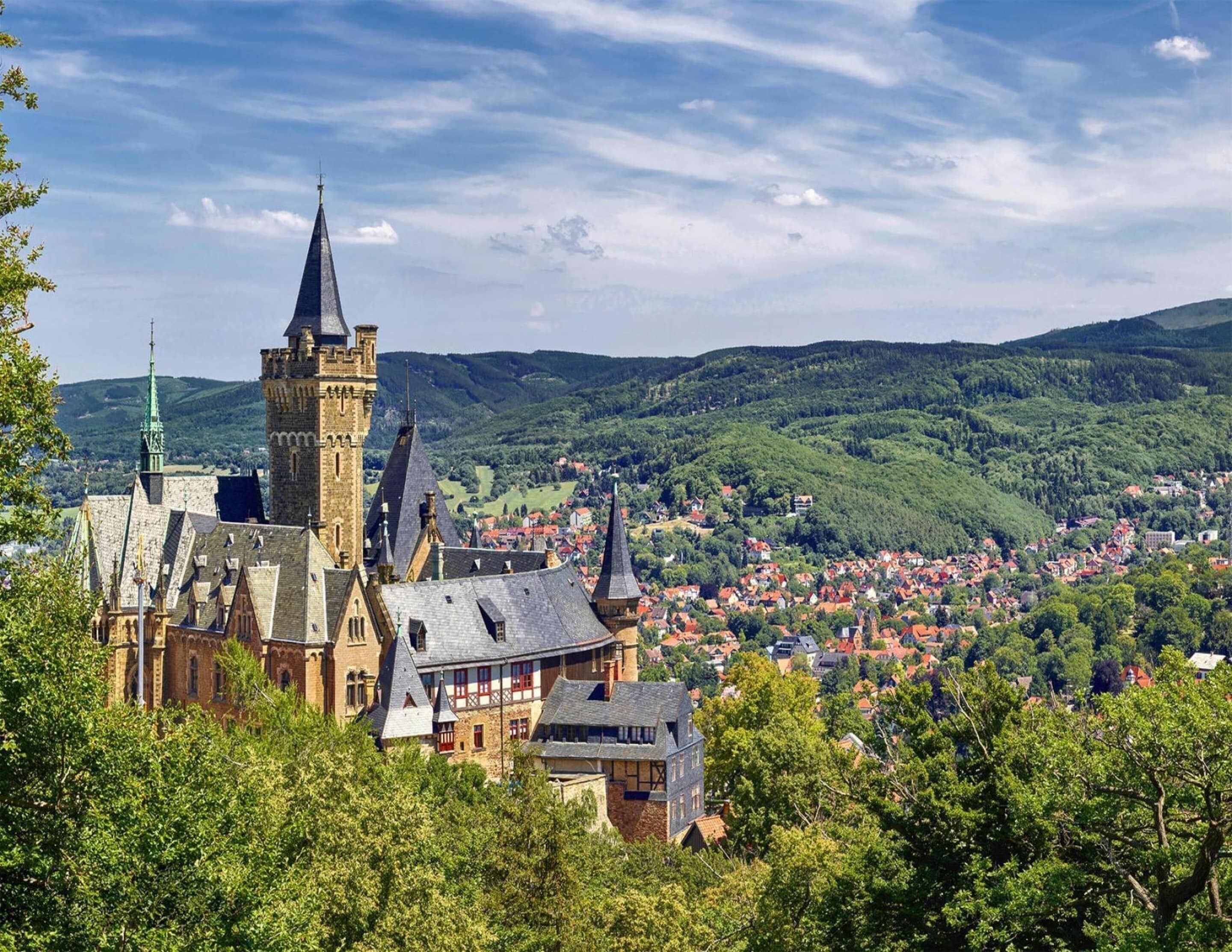 A historic town with a prominent castle featuring multiple towers and a church with a spire.