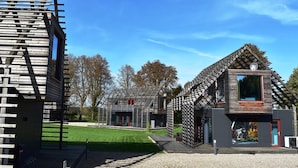 A modern building with a unique wooden lattice facade, a central courtyard, and a small outdoor area with a dog. - Chalet, Wendorf (Kuhlen-Wendorf)