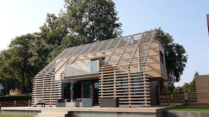 A modern house with a slatted roof, a covered porch, and a small outdoor seating area. - Chalet, Wendorf (Kuhlen-Wendorf)