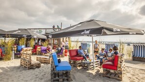Outdoor seating with umbrellas, wooden furniture, and a beachside view. - Ferienhaus im Ostseeresort Dampland in Perfekter Lage (Damp)