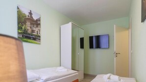 A hotel room with two beds, a television, and a wardrobe. - Apartment Schlossblick, Wernigerode (Wernigerode)