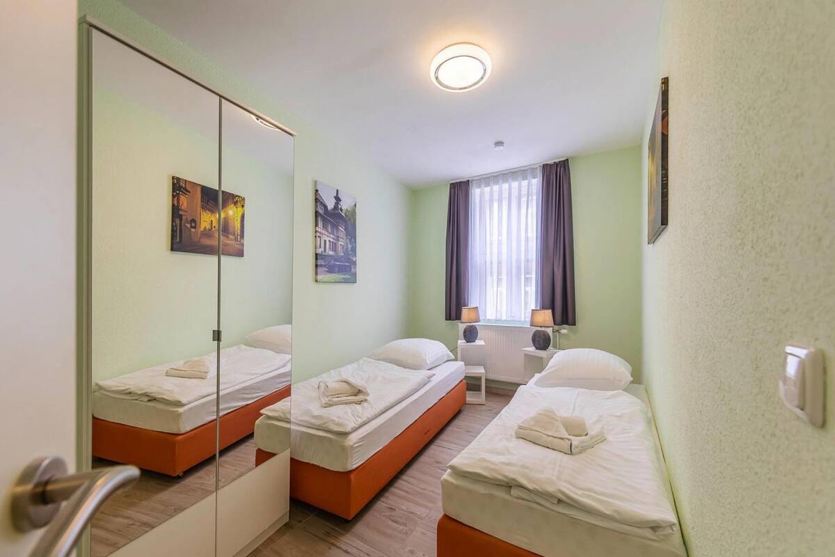 A hotel room with two beds, a large mirror, and a window with curtains.