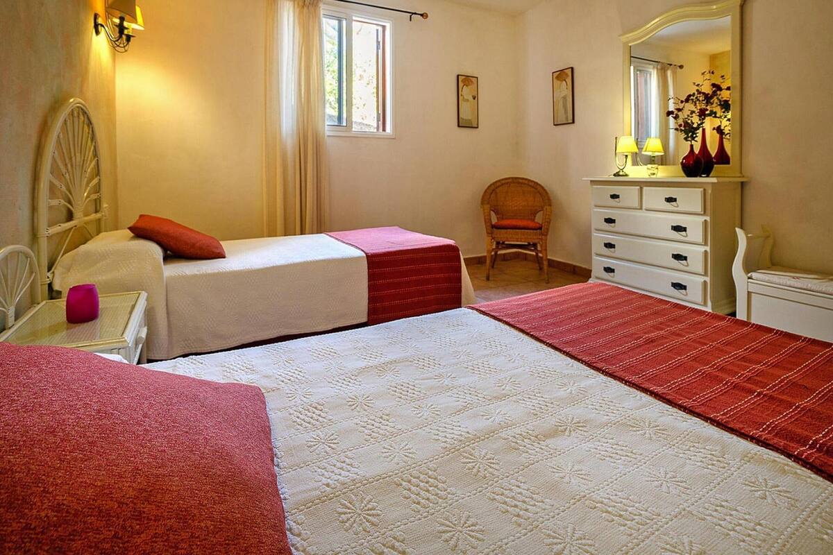 Een slaapkamer met twee bedden, een stoel, een dressoir en een spiegel.