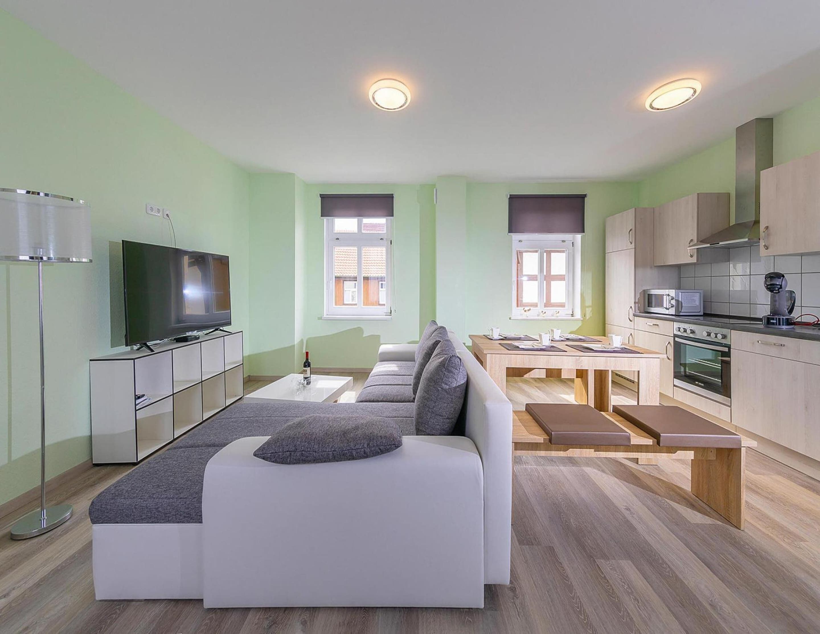 Una sala de estar moderna con sofá, televisión y comedor.