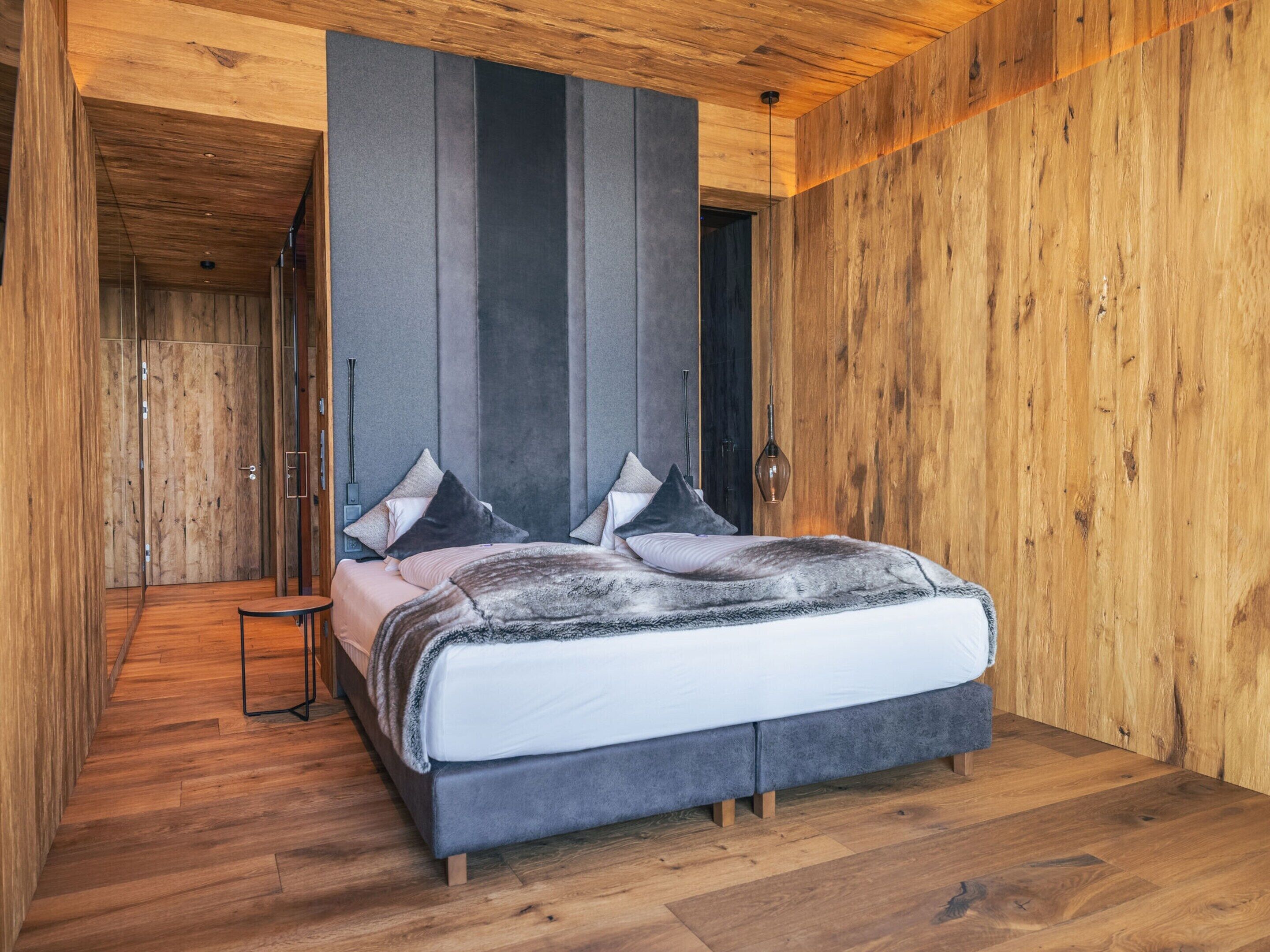 A bedroom with a bed, wooden walls, and a wooden floor.
