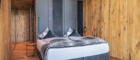 A bedroom with a bed, wooden walls, and a wooden floor.