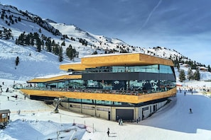 A modern ski resort building with a glass facade, a flat roof, and a ski slope in the background. - Apartment in Kaltenbach at the ski Slope (Kaltenbach)