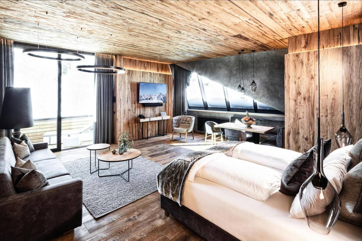 Una habitación moderna con techo de madera, un sofá, una cama, un televisor y un comedor.