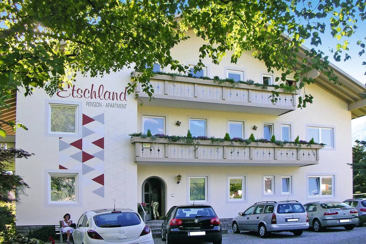 A multi-story building with a sign reading "Etschland Pension - Apartment".