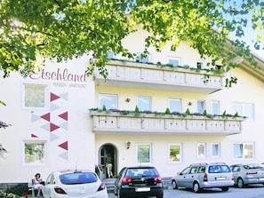 A multi-story building with balconies, a sign for 'Etschland Pension - Apartment,' and several parked cars. - Apartment in Dorf Tirol Near Tennis Court (Tirolo)