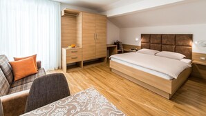 Een moderne hotelkamer met een groot bed, een bureau, een kledingkast en een zithoek.