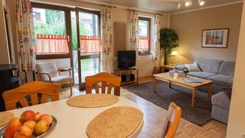 A cozy living room with a sofa, TV, and a dining table with apples.