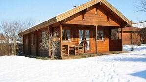 A wooden cabin with a porch and large windows, surrounded by snow. - Holiday Homes Lauterdorfle, Hayingen (Hayingen)