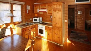 A wooden cabin interior with a kitchen area, dining table, and chairs. - Holiday Homes Lauterdorfle, Hayingen (Hayingen)