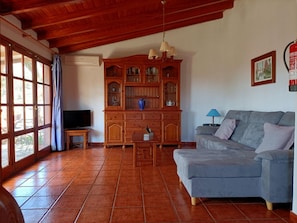 Uma sala de estar com um armário de madeira, uma televisão, um sofá e uma mesa.