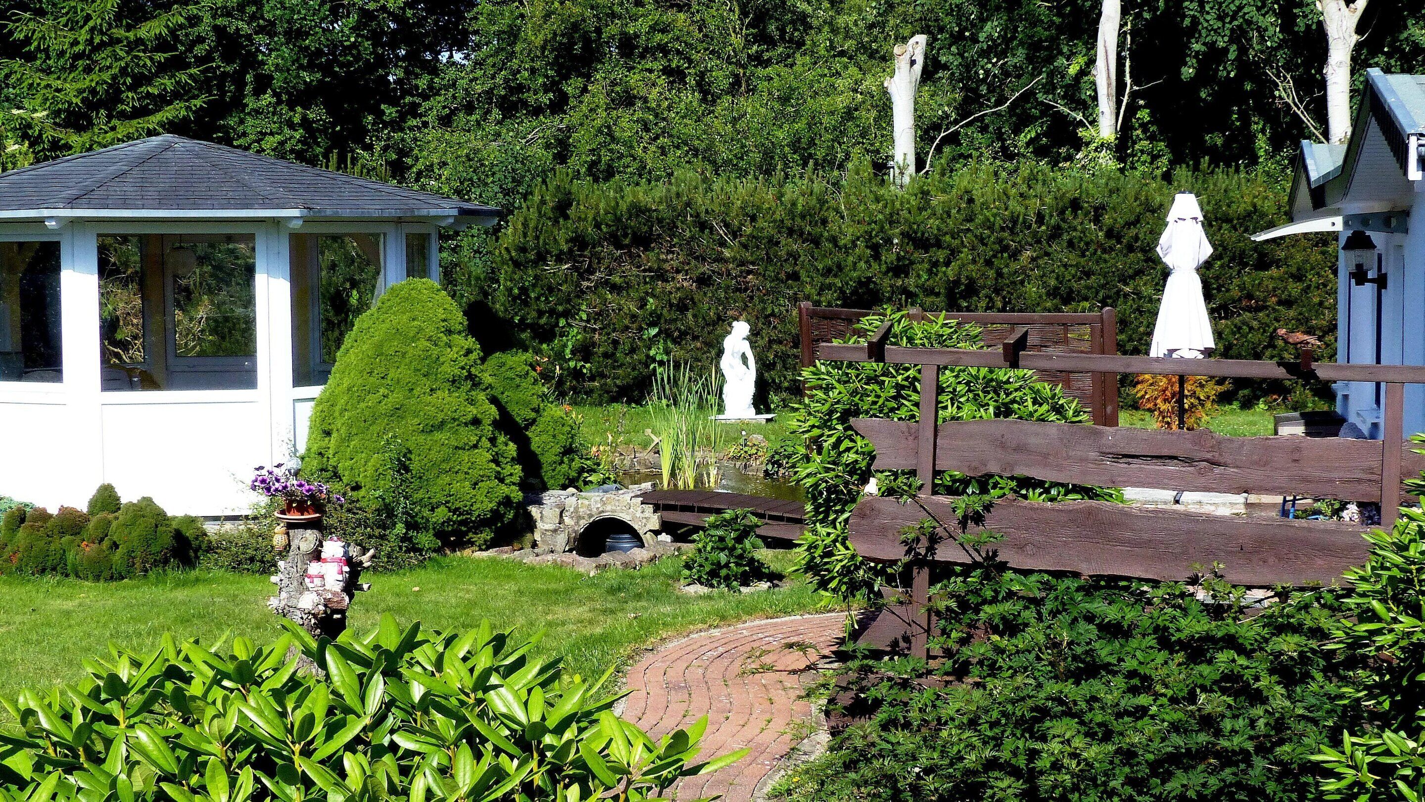 Un jardín con un pabellón, estatuas y una cerca de madera.