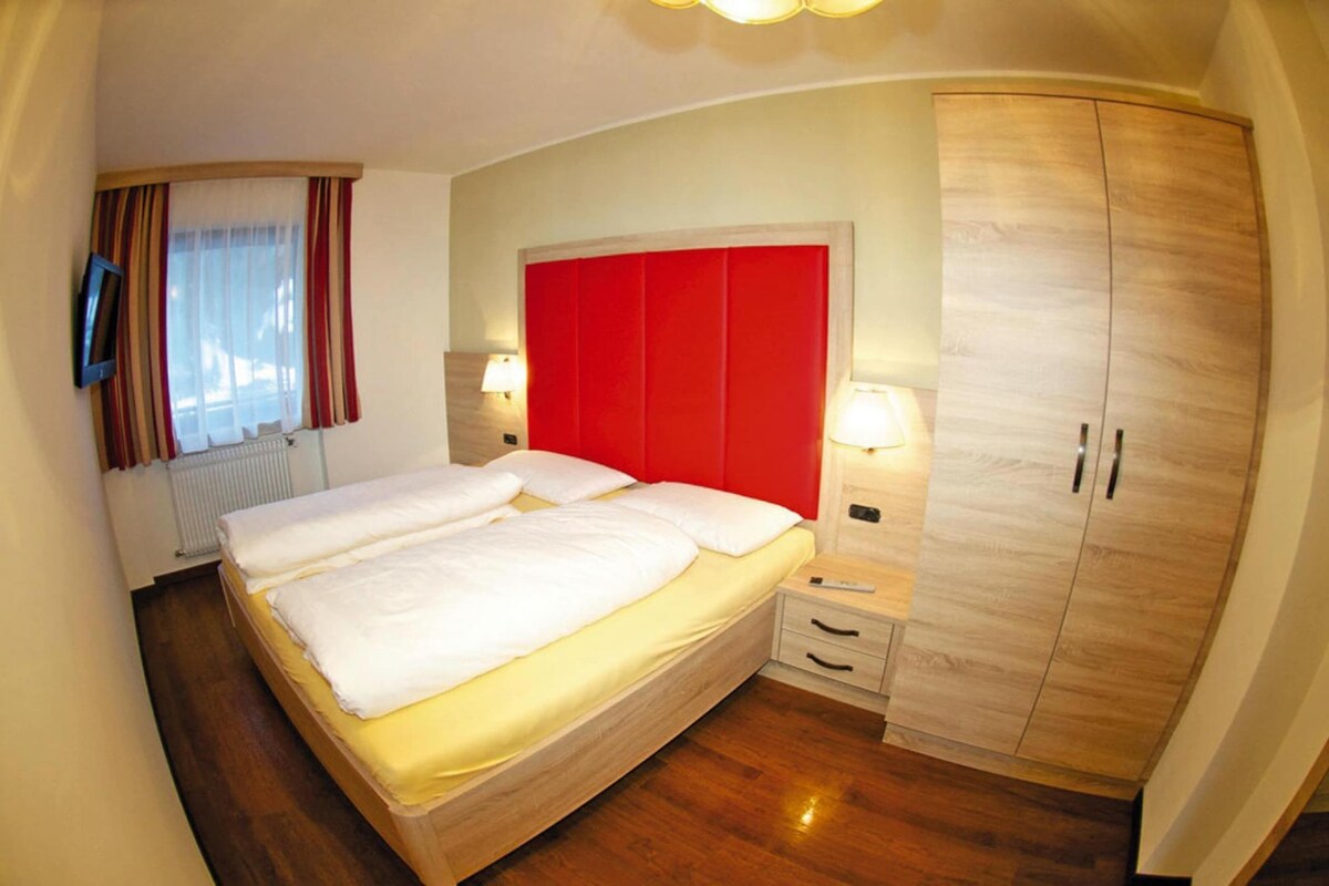Une chambre d’hôtel avec un grand lit, une armoire en bois, des lampes de chevet et un téléviseur fixé au mur.