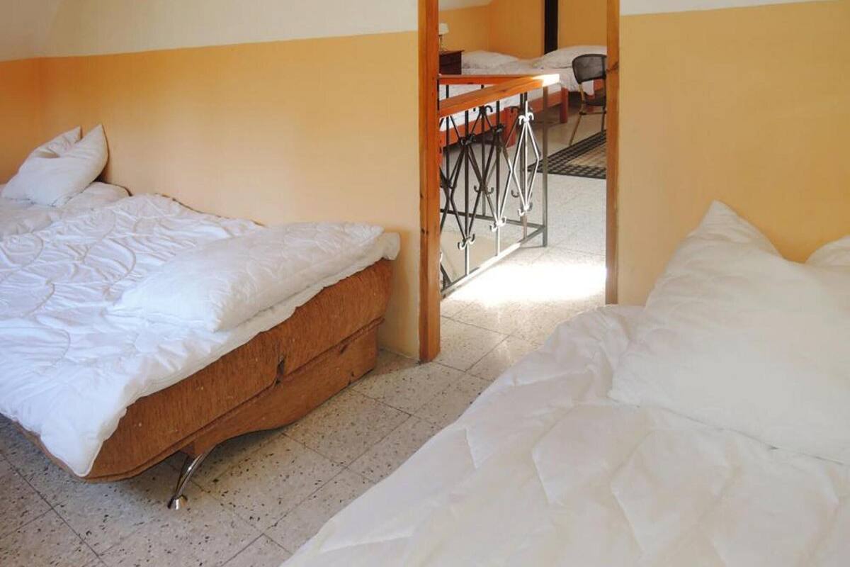 A dormitory room with two beds, a wooden desk, and a chair.
