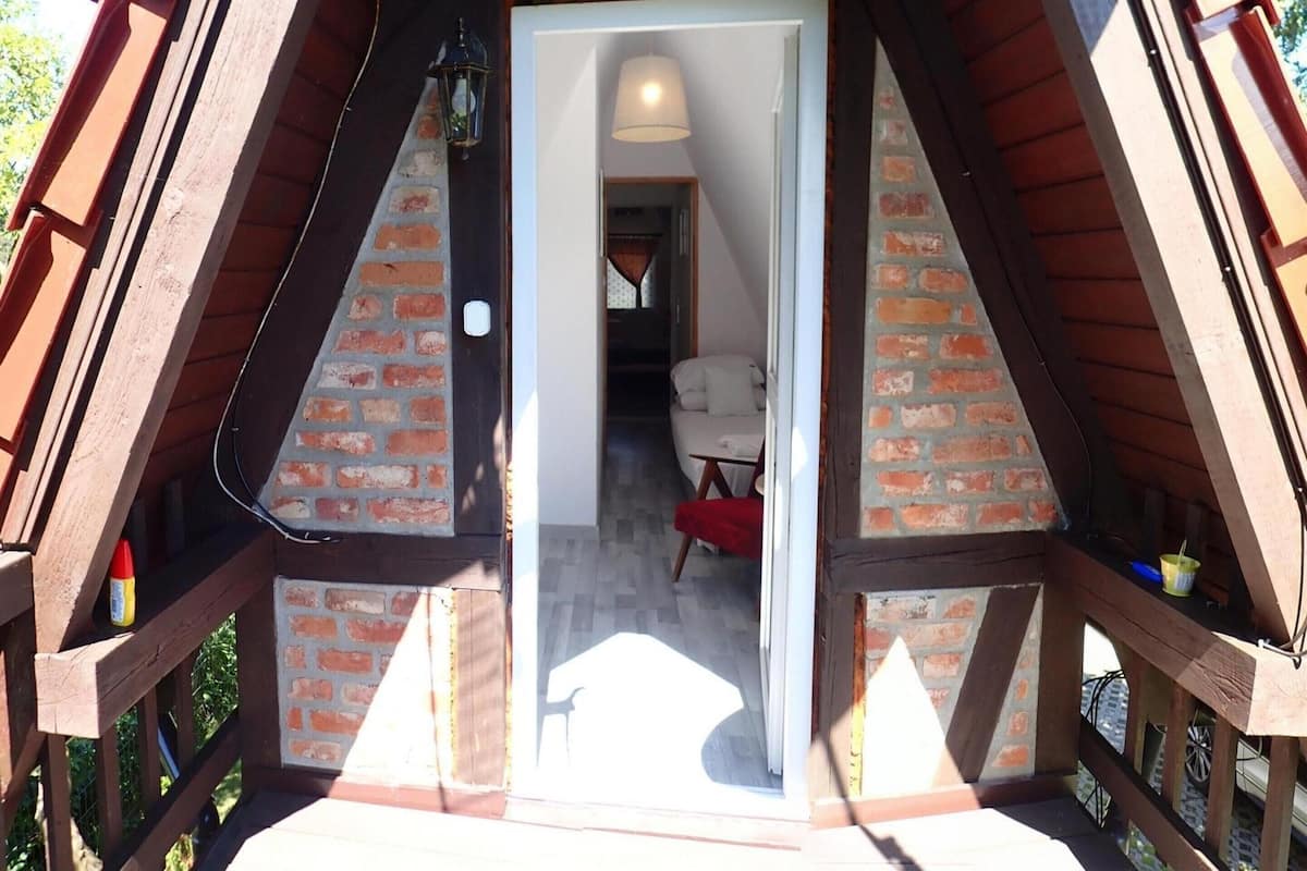 Ein Dachzimmer aus Holz mit Backsteinwänden, einer weißen Tür und einem kleinen Bett.
