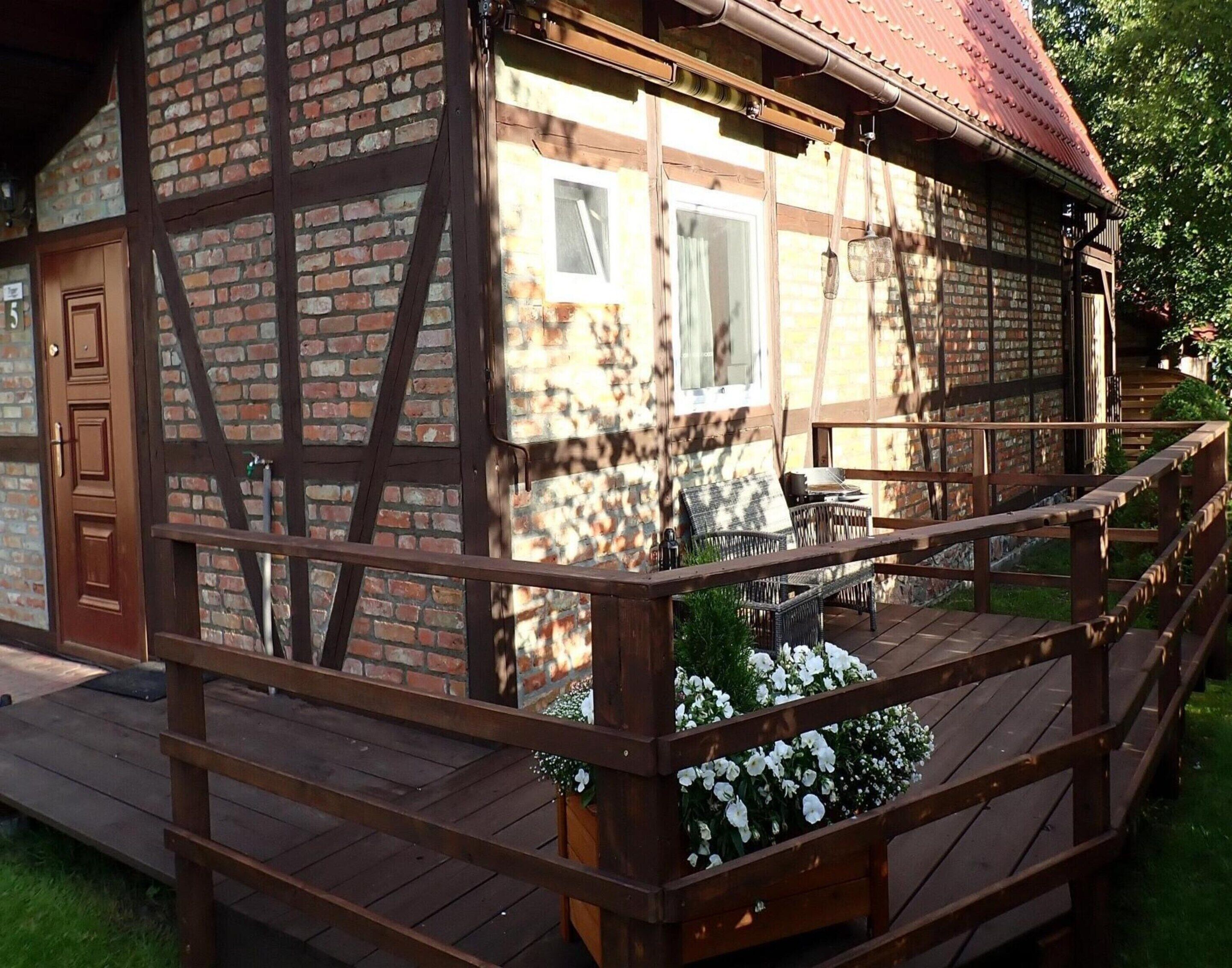 A traditional half-timbered house with a wooden deck and white flowers in planters.