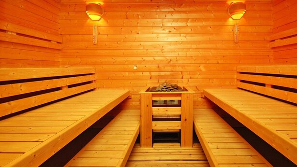 A sauna with wooden benches and a central table with logs. - Ferienpark Harz in Hasselfelde (Oberharz am Brocken)