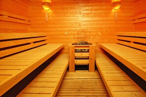 A sauna with wooden benches and a central table with logs. - Ferienpark Harz in Hasselfelde (Oberharz am Brocken)