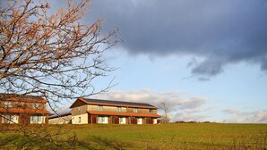 A modern two-story house with a sloped roof and solar panels, surrounded by a grassy field and a tree. - Ferienpark Harz in Hasselfelde (Oberharz am Brocken)