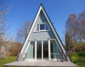 A triangular house with a deck, sliding glass doors, and outdoor seating. - Cottage, Steam (Damp)