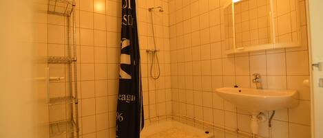 Ein Badezimmer mit Dusche, Waschbecken und Spiegel.