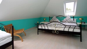 A bedroom with a bed, a chair, a nightstand, and a window. - Apartment House at Kiessee, Westerholt (Nenndorf)
