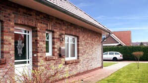 A brick house with a tiled roof, a front door, and a small garden with a lawn and a pathway. - Apartment House at Kiessee, Westerholt (Nenndorf)