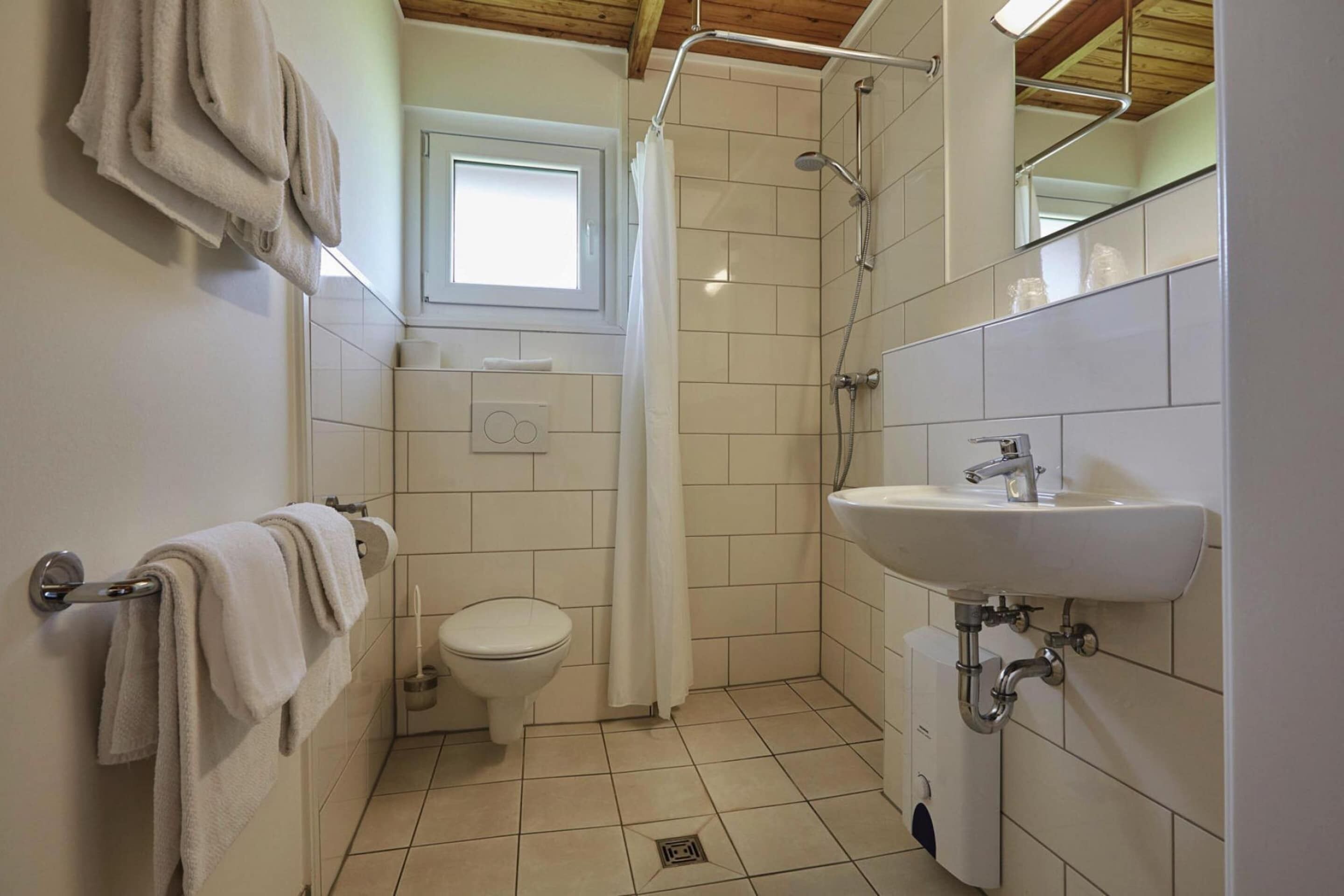 Une salle de bain équipée de toilettes, d’une douche, d’un lavabo et de serviettes.