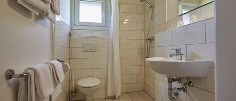 Une salle de bain équipée de toilettes, d’une douche, d’un lavabo et de serviettes.