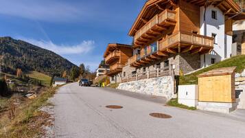 A row of wooden chalet-style buildings with balconies, a stone wall, and a clear sky.