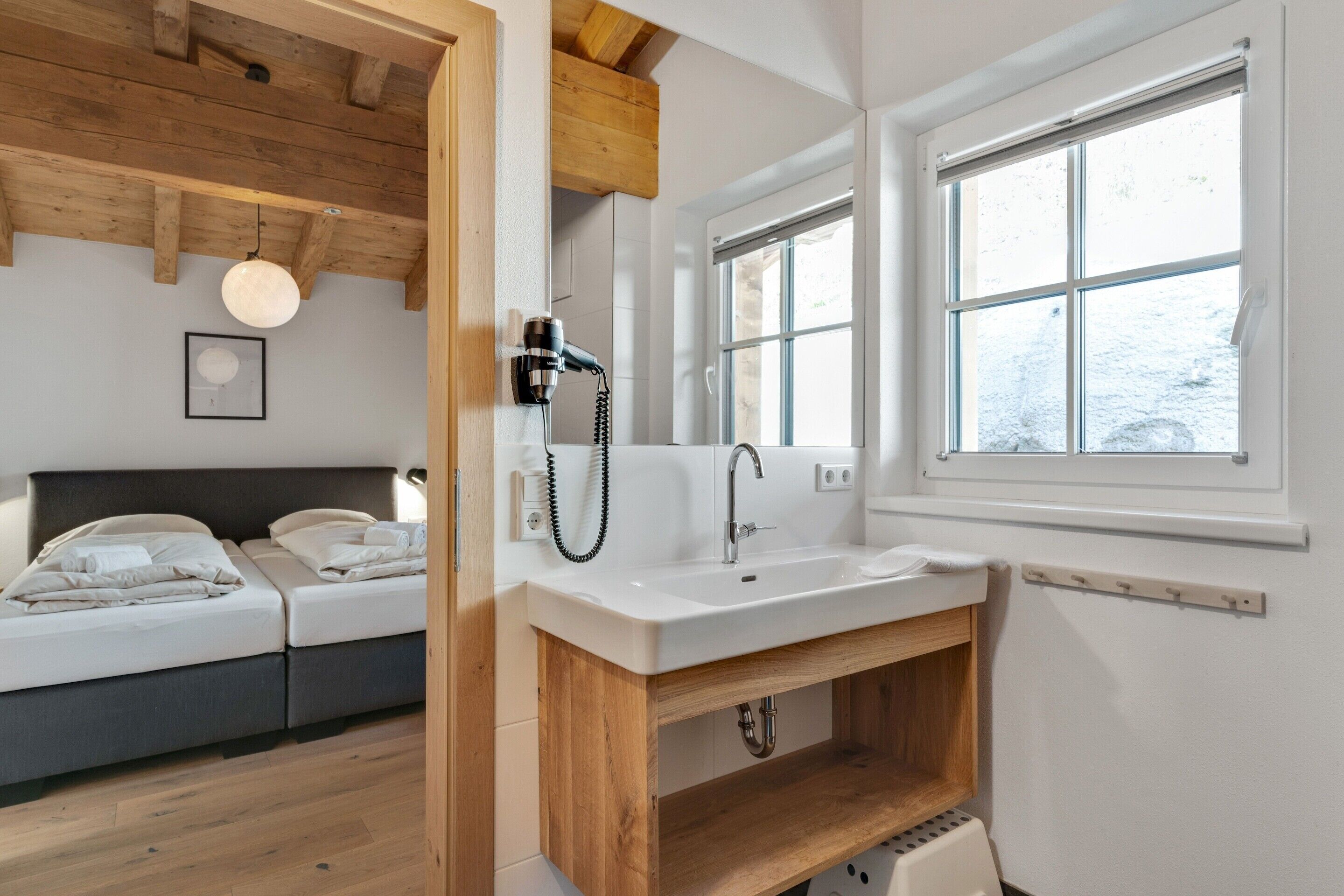 A modern bedroom with a wooden ceiling, a white bed, and a large window.