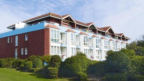 Ett hotell med flera våningar, en fasad av tegel, balkonger och ett platt tak.