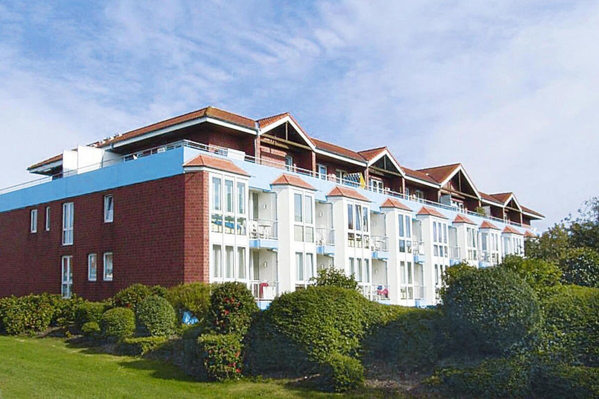 A multi-story hotel with a red brick facade, white balconies, and a flat roof.