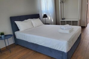Un lit bien fait, avec du linge de lit blanc, une table de chevet avec une lampe et une petite plante.