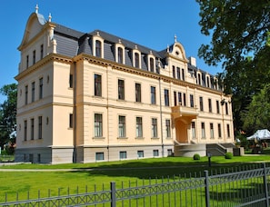 Un grande edificio storico con una facciata simmetrica, numerose finestre e un ingresso centrale con una scalinata.