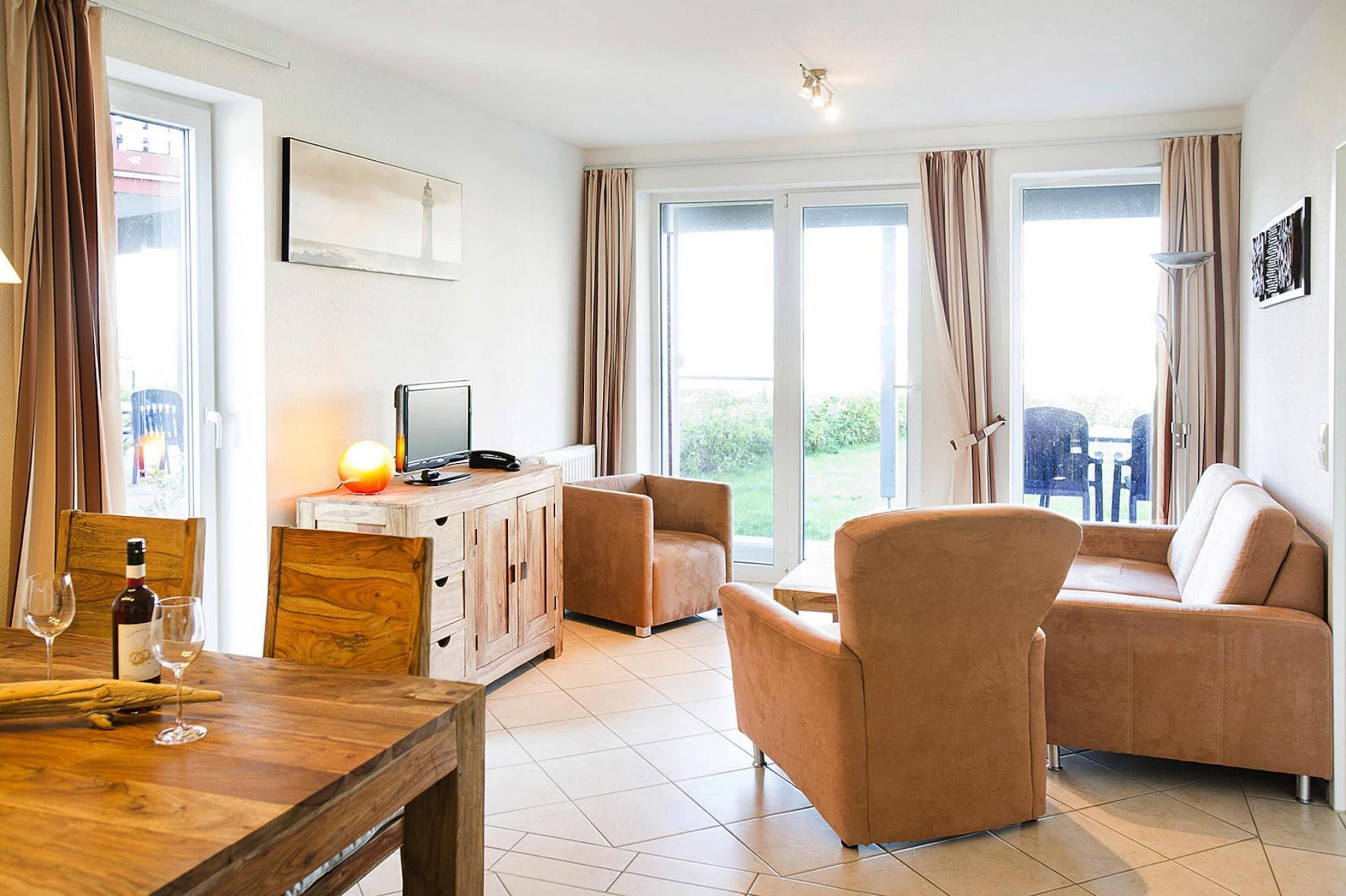 Un soggiorno moderno con un tavolo da pranzo in legno, due divani, una televisione e un balcone con tende.
