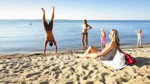 Ein Strand mit entspannten Personen und einem Mann, der einen Handstand macht.