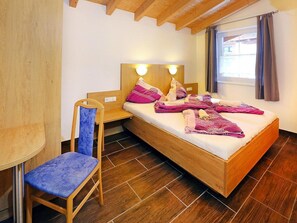 Una habitación pequeña y acogedora con una cama de madera, una silla y una mesita de noche.