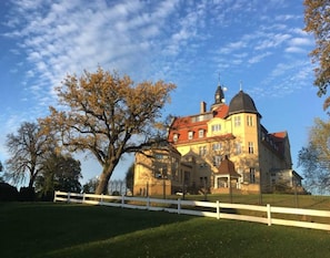 A large, historic building with a prominent tower and a large tree in the foreground. - Chalet, Wendorf (Kuhlen-Wendorf)