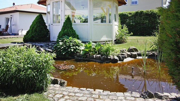 A house with a conservatory, a pond, and a well-maintained garden. - Apartment House Nicole, Zinnowitz (Zinnowitz)