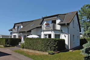 A two-story house with a balcony, a covered porch, and a well-maintained lawn. - Apartment House Nicole, Zinnowitz (Zinnowitz)