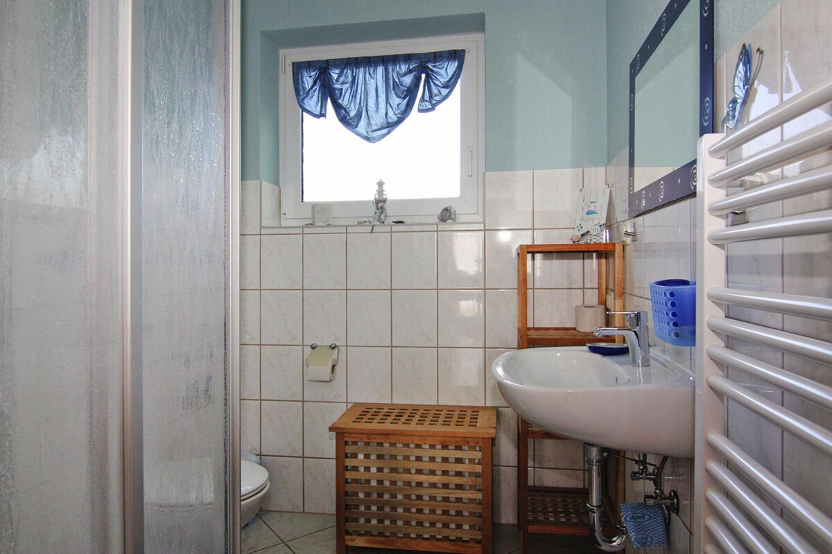 Een badkamer met toilet, wastafel en raam met blauwe gordijnen.