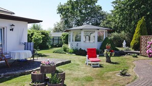 A garden with a gazebo, a red chair, and a white table. - Apartment House Nicole, Zinnowitz (Zinnowitz)