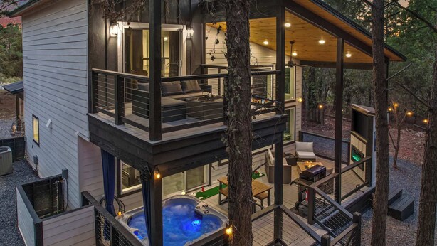 Une cabane à deux étages dotée d’un bain à remous, d’un espace salon extérieur et d’une terrasse.