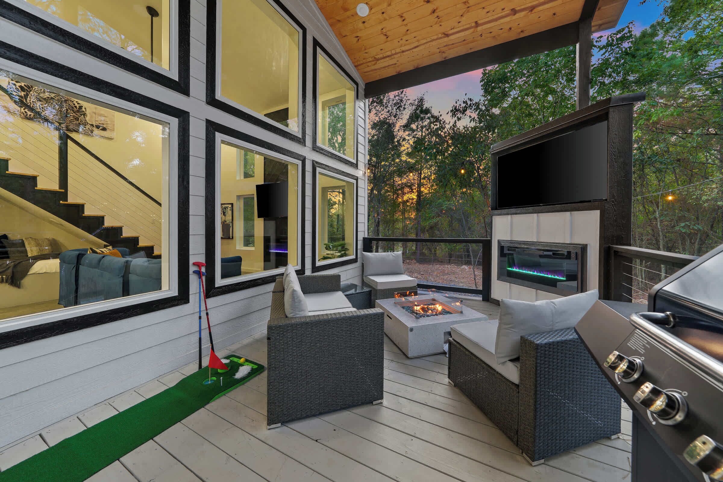 A modern outdoor deck with a fireplace, seating area, and a grill.