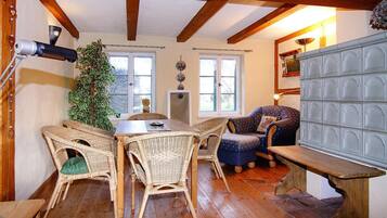 Uma sala de jantar com uma mesa de madeira, cadeiras de vime, um sofá azul e um banco.